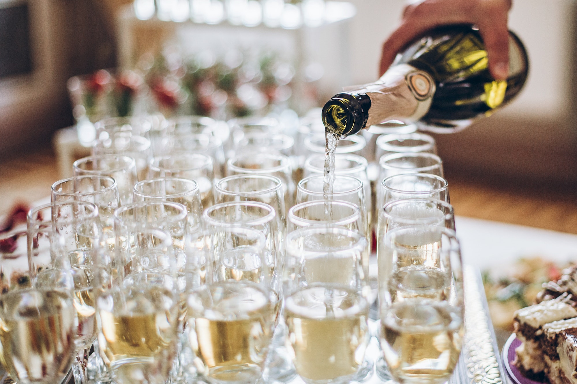 Waiter pouring champagne in stylish glasses at luxury wedding reception